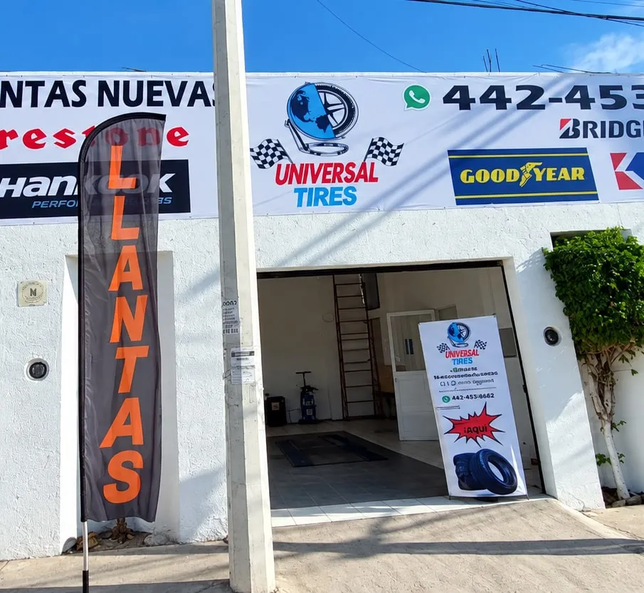 La fachada de Universal Tires, con su marca en el letrero y la bandera de «Llantas» en la entrada.