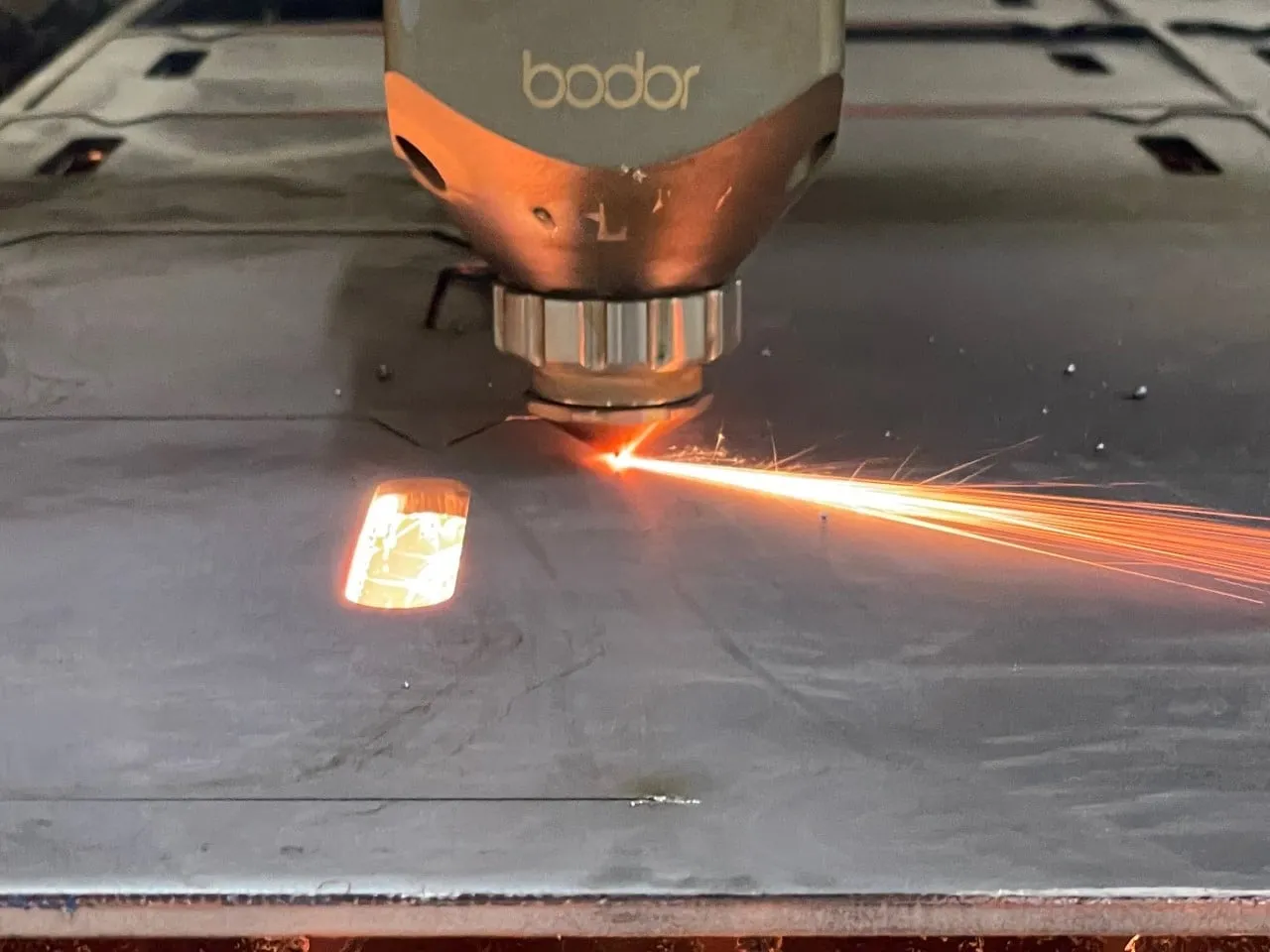 El cabezal del láser de Quantum Láser cortando una lámina de acero, entre chispas.